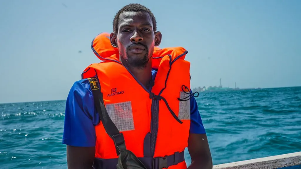 A fisherman wearing an orange life jacket aboard a boat at sea, file photo