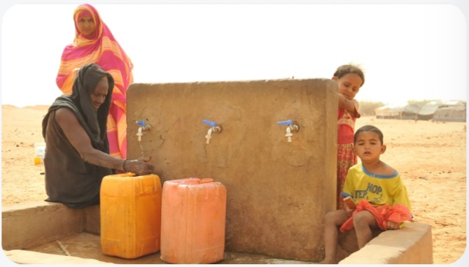 Women and children around a water point with jerrycans