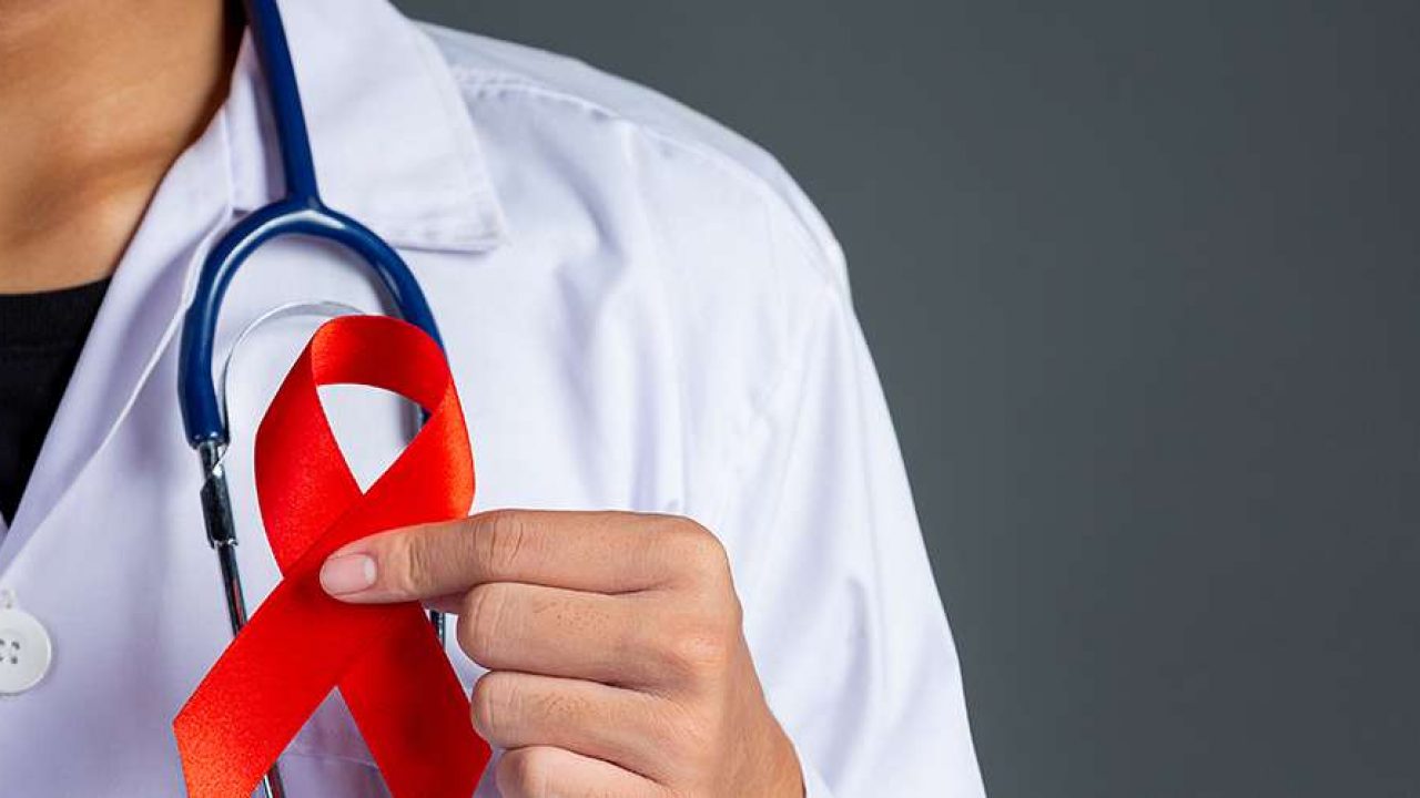A doctor in a white coat with a stethoscope holding a red ribbon, the symbol of the fight against AIDS, illustrative file image