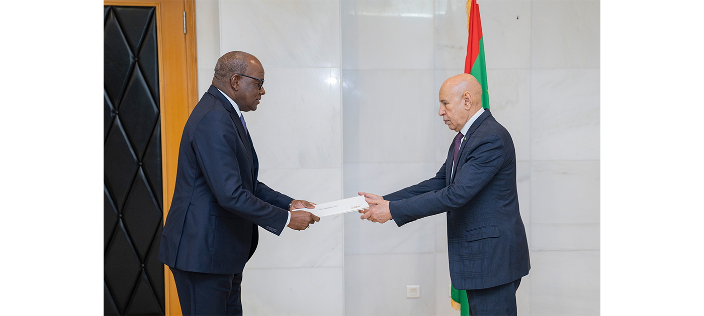 President Ghazouani receives a letter from an ambassador in front of the Mauritanian flag