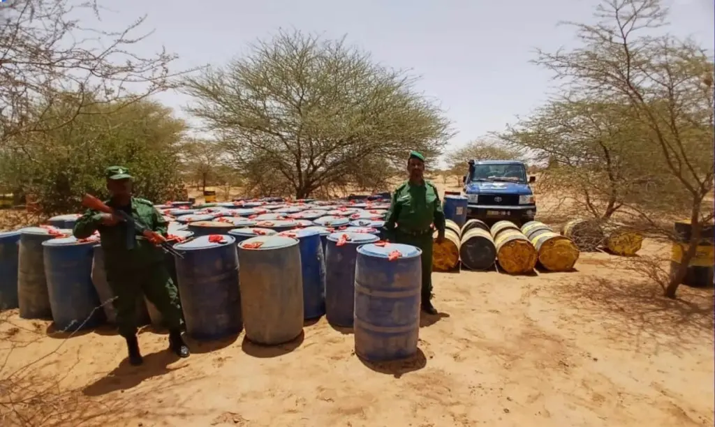 Gendarmes beside seized fuel drums