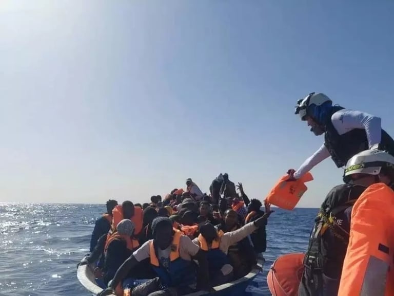 Rescuers hand life jackets to migrants on a crowded boat at sea