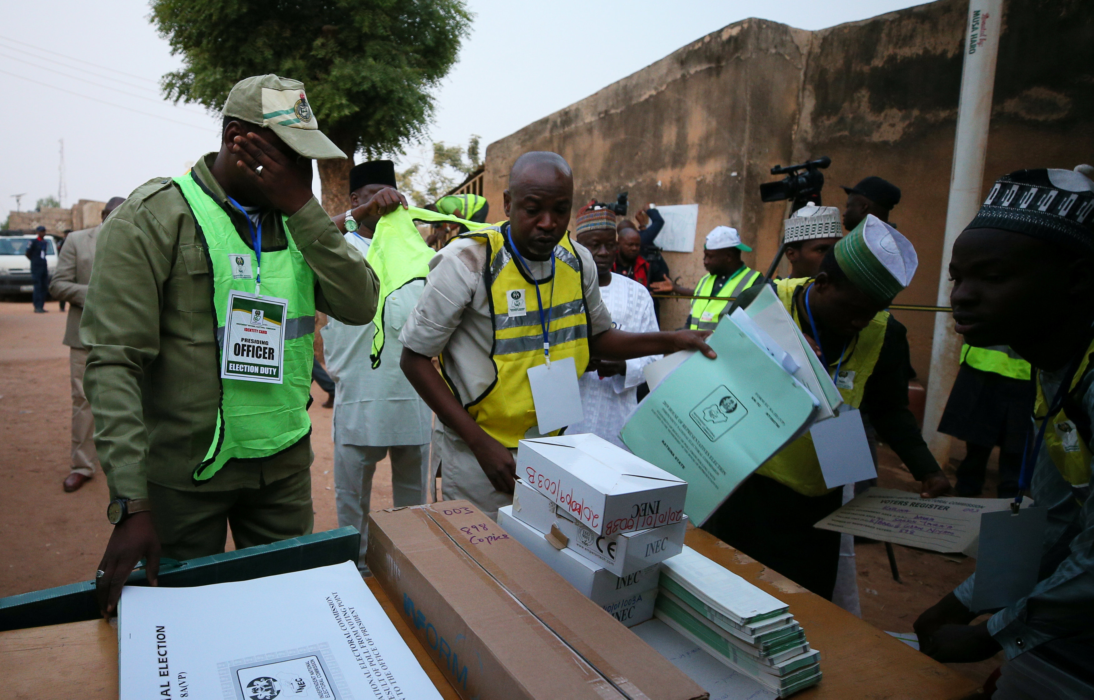Nigerian electoral commission staff arrange ballot boxes and voting documents outside a polling unit