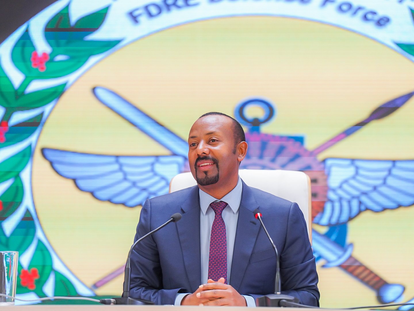 Ethiopian Prime Minister Abiy Ahmed seated behind microphones in front of the defence force emblem, file photo
