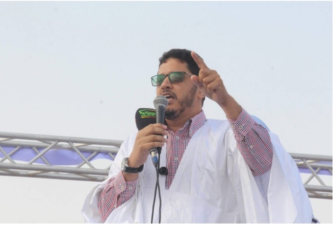 A man speaks into a microphone at an outdoor rally