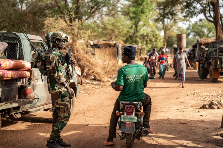 A Senegalese soldier in camouflage and helmet next to a pick-up on a dirt road, illustrative file image