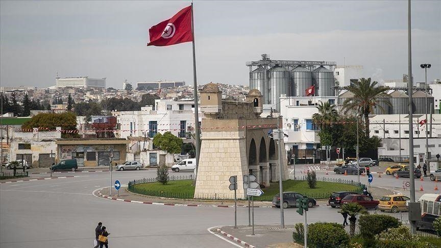 A roundabout in Tunis with a Tunisian flag and grain silos in the background