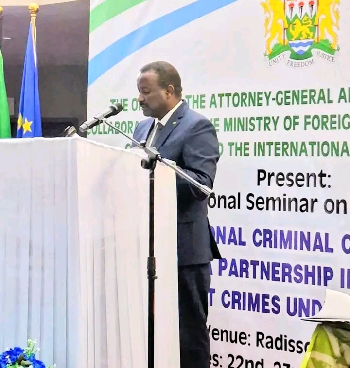 The justice minister speaks at the podium in front of the ICC regional seminar banner