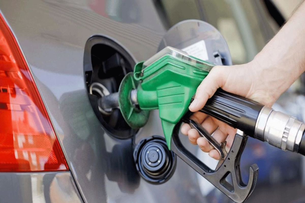 A hand holding a green fuel pump nozzle in a car's tank, file photo