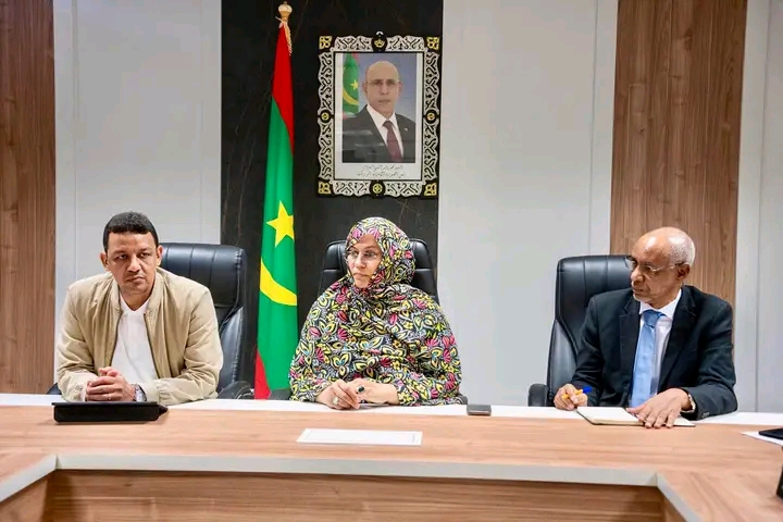 The health minister flanked by two officials at a meeting table