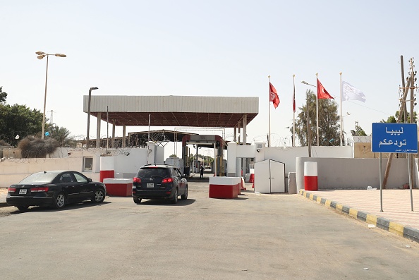 Entrance to a land border crossing between Tunisia and Libya, with cars and a sign reading Libya bids you farewell, file photo