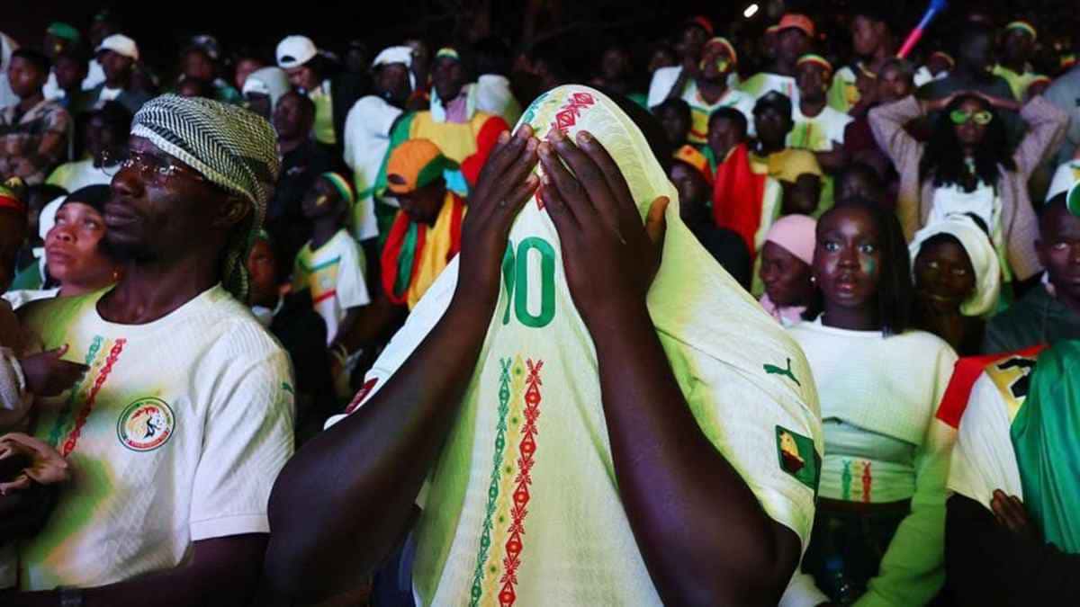 A crowd of Senegal supporters in national team shirts, one covering his face with a shirt, file photo