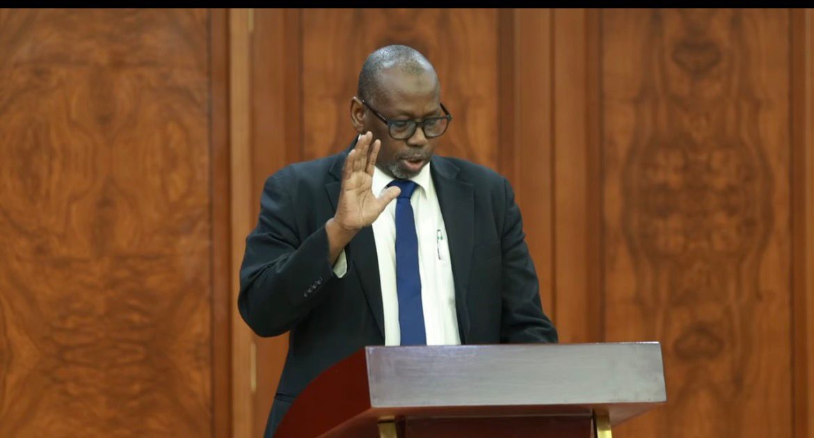 A man raises his right hand to take an oath behind a lectern