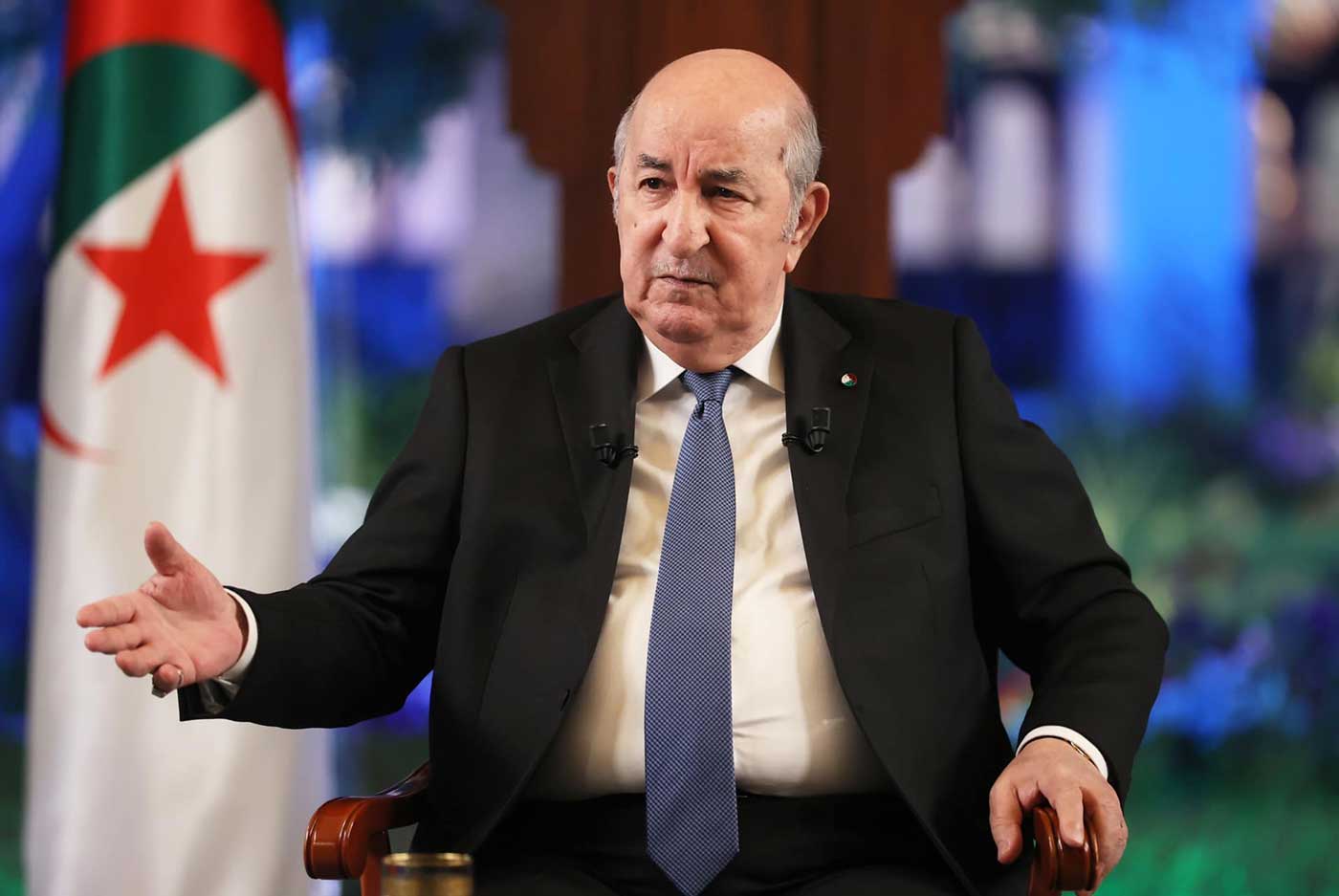 Algerian President Abdelmadjid Tebboune seated in front of the Algerian flag