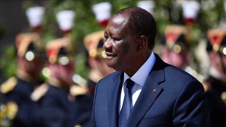 Ivorian President Alassane Ouattara in a dark blue suit in front of an honour guard with red and gold helmets, file photo