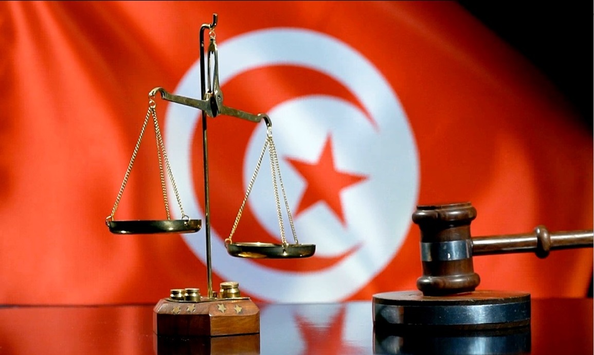 Scales of justice and a judge's gavel in front of the red Tunisian flag, file illustration