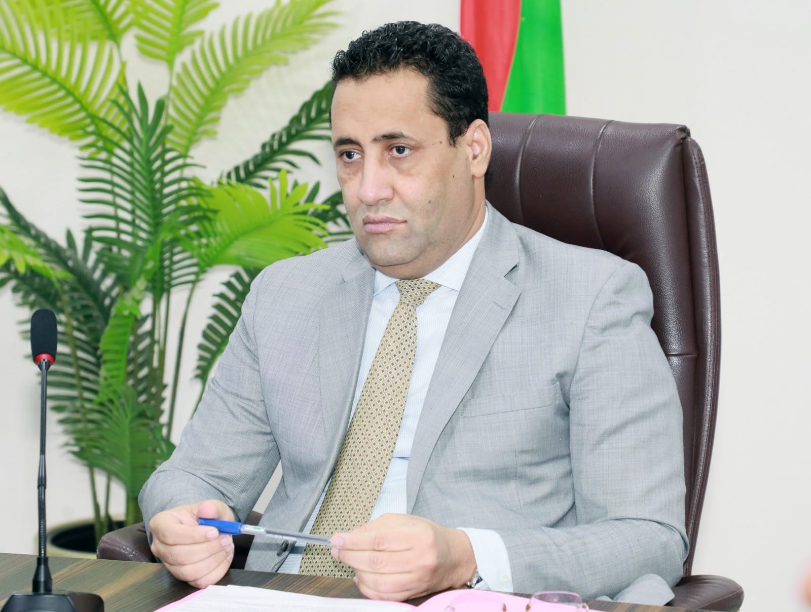 The prime minister seated at a desk in front of the Mauritanian flag