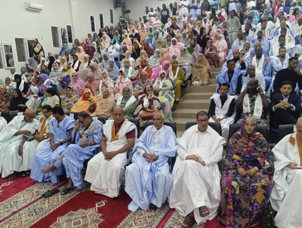 An audience of men and women in a hall during a cultural event