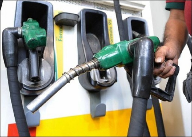 A hand holding a fuel nozzle beside other nozzles at a filling station, file photo