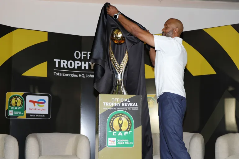A man pulls a black cover off the golden CAF Champions League trophy at the official reveal in Johannesburg, file photo