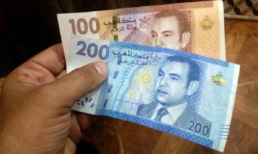 A hand holding two Moroccan banknotes of 100 and 200 dirhams, file photo