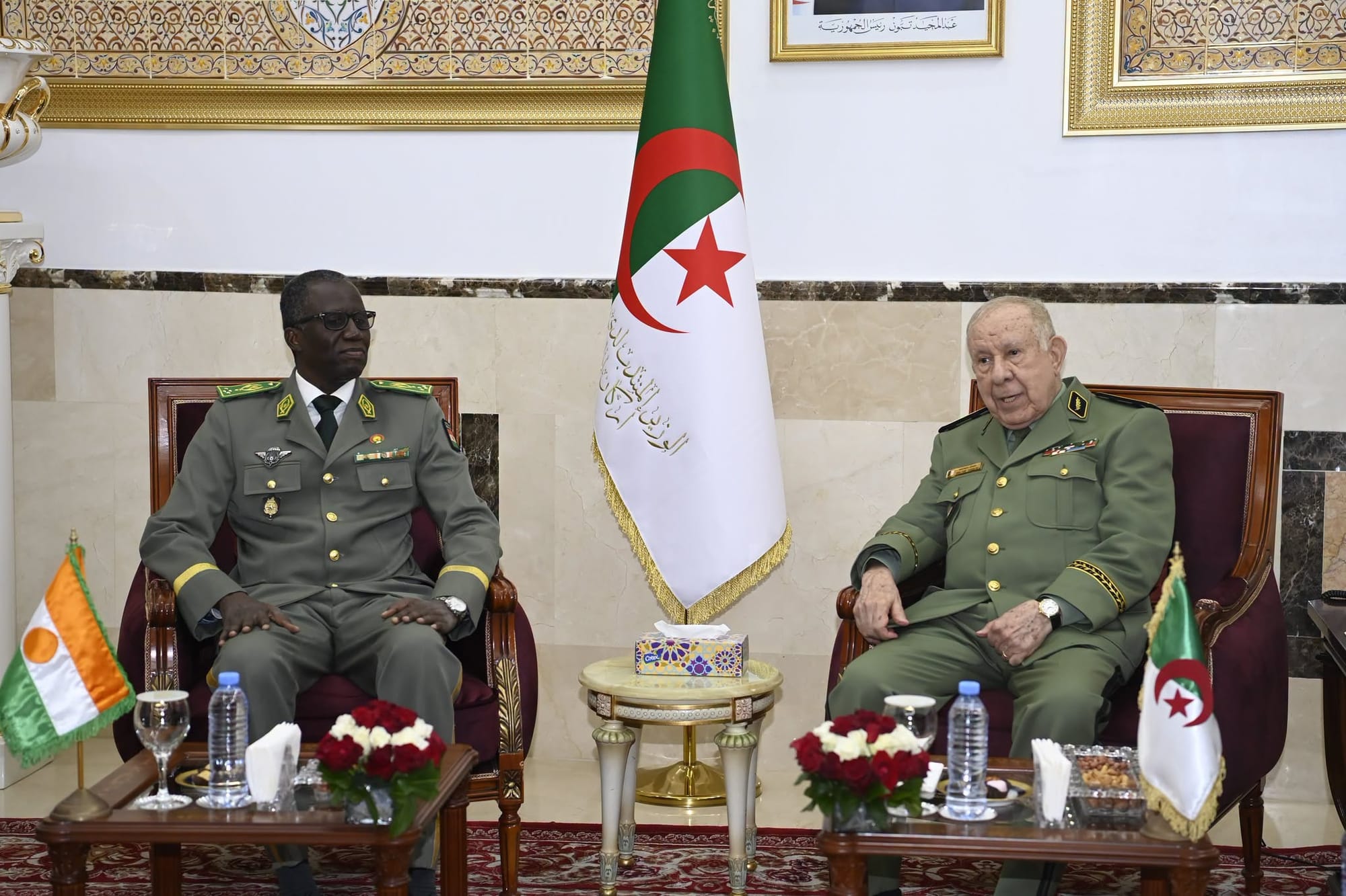 Algeria's army chief of staff seated beside a Nigerien officer in front of both countries' flags