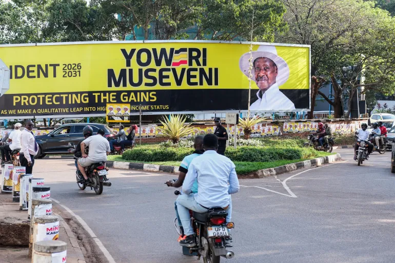Motorcycles and cars on a street in Kampala near a large election billboard, file photo
