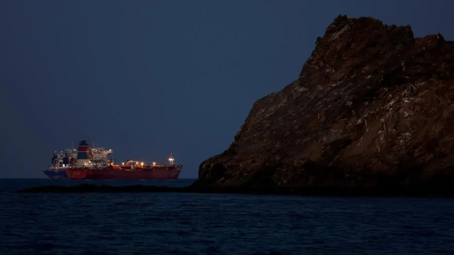 An oil tanker sailing near a rocky coast at dusk, file photo
