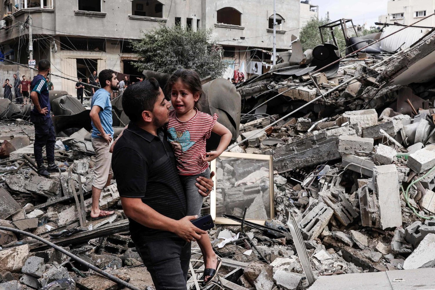 A man carries a crying girl through the rubble of destroyed buildings in the Gaza Strip, file photo