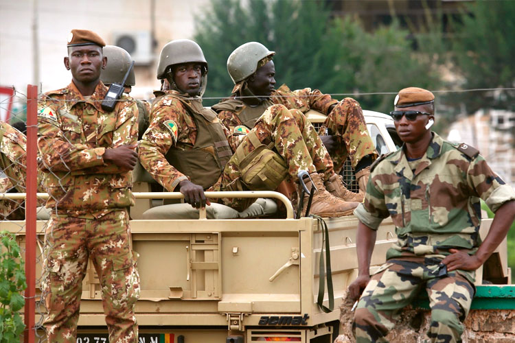 Malian soldiers in camouflage on and beside a military vehicle, file photo