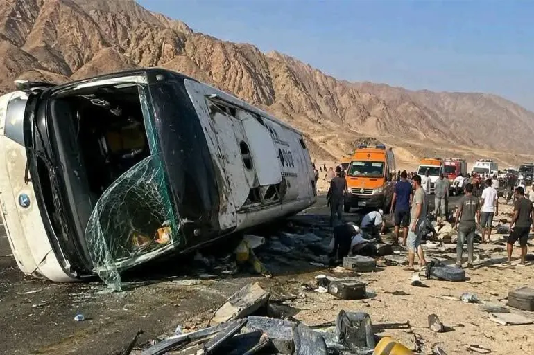 A passenger bus lying on its side by a mountain road surrounded by rescuers and onlookers, file photo of an earlier crash in Egypt