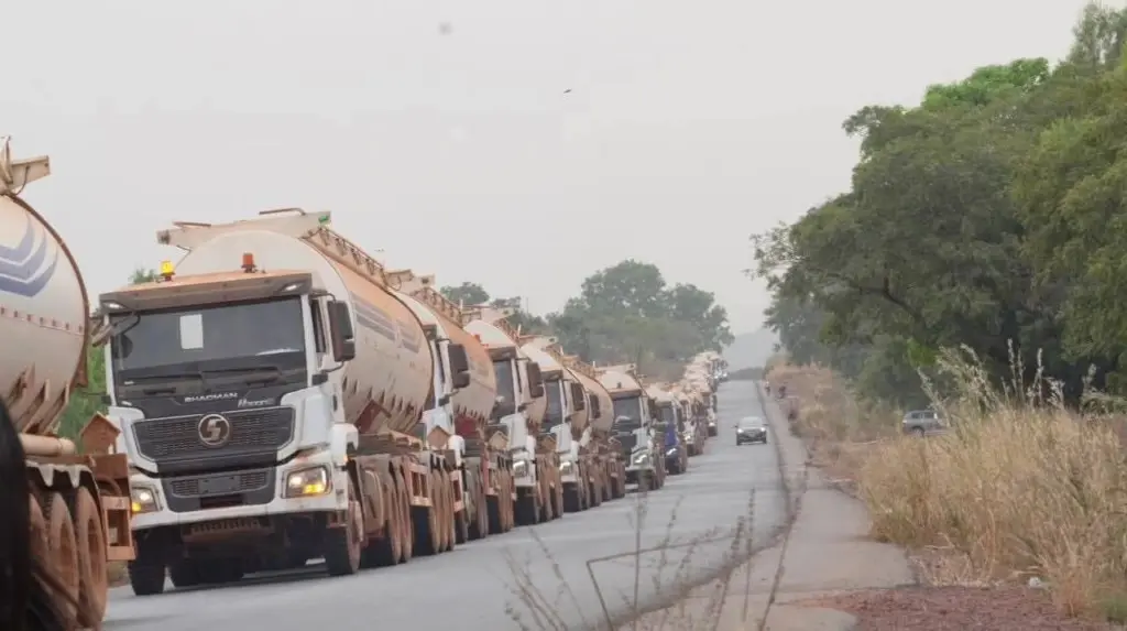 A long line of fuel tanker trucks on a tree-lined road, file photo