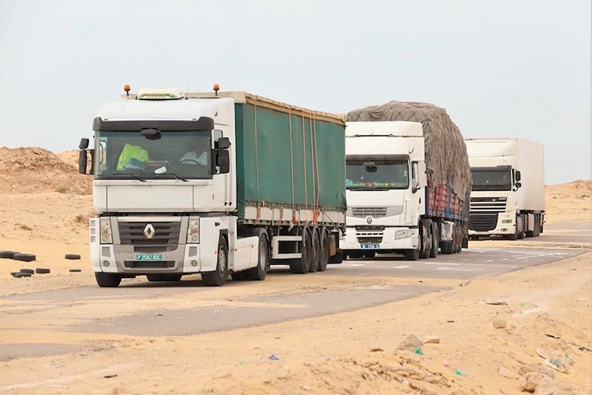 Three freight trucks driving on a road lined with sand, file photo