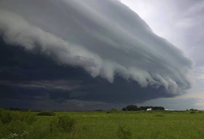 A thick storm cloud over a green field