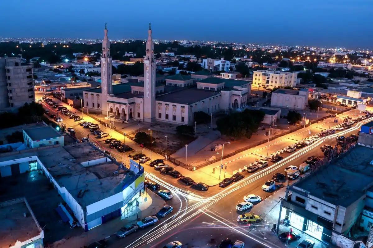 A cityscape at dusk, with a mosque and surrounding streets