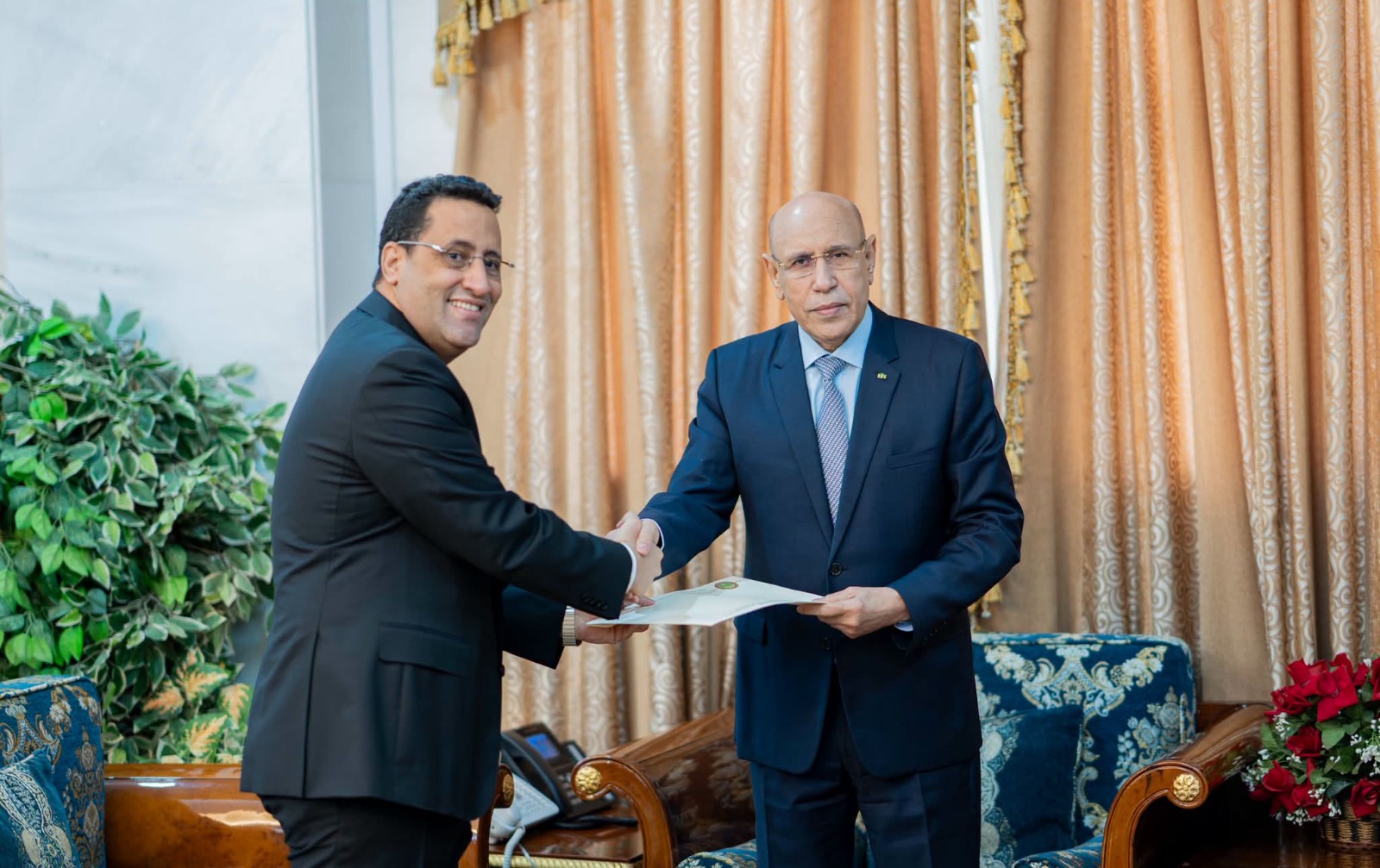 Archive photograph of two officials exchanging a document, accompanying the report on Mauritania's government changes.
